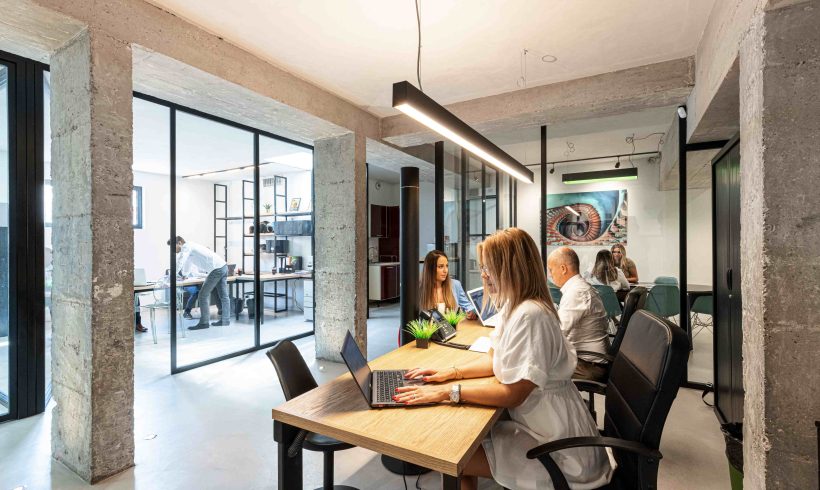 On aperçoit derrière un bureau les collaborateurs du groupe Concept Patrimoine en train de travailler. On y voit en premier plan une femme qui est assise à son bureau et tape sur son ordinateur portable. Au second plan, un homme et une femme assis face à face à un bureau et discutent.